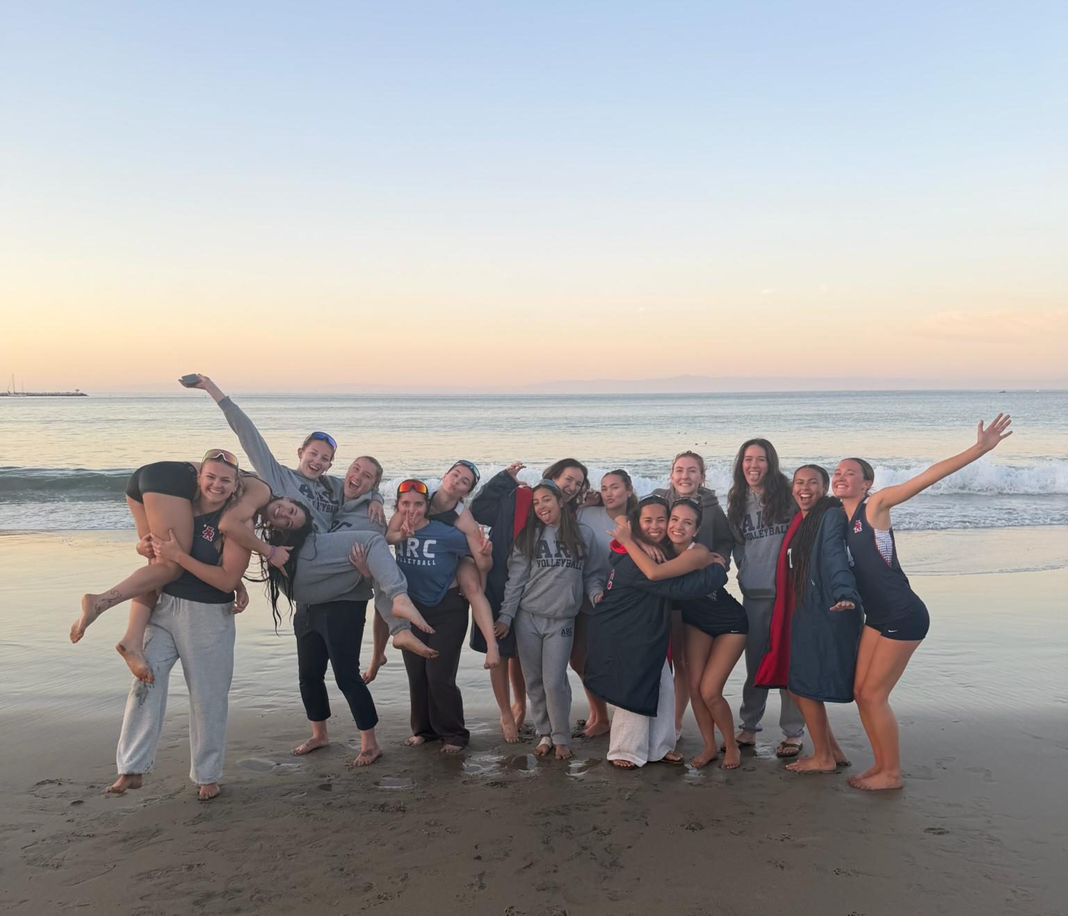ARC Beach Volleyball team photo in front of the sunset and waters of Monterey Bay.