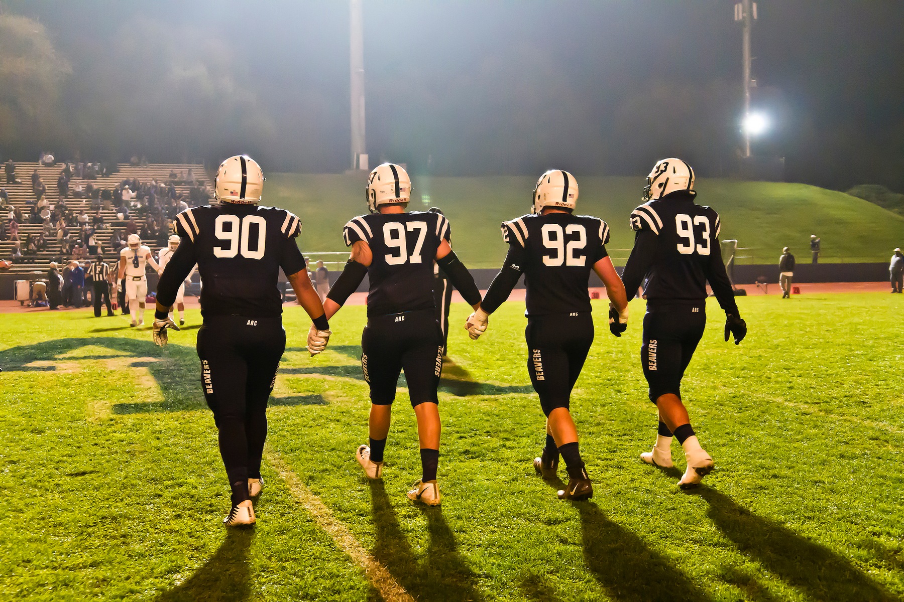 Football players 90, 97, 92, and 93 walking.